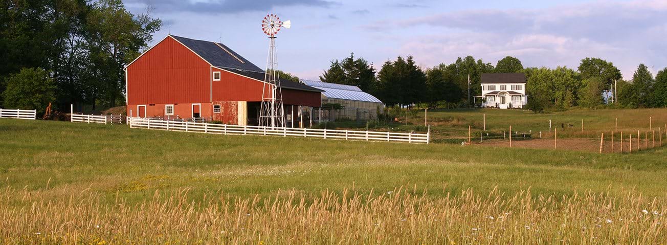 Photo of red barn with white farm house in background