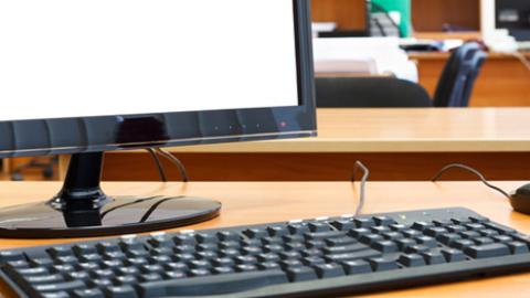 Monitor, keyboard and mouse set up on a desk.